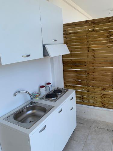 uma cozinha branca com um lavatório e um balcão em La caccetta em Procida