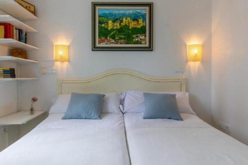 ein Schlafzimmer mit einem weißen Bett mit zwei blauen Kissen in der Unterkunft Oliva Nova Villa Mar in Oliva