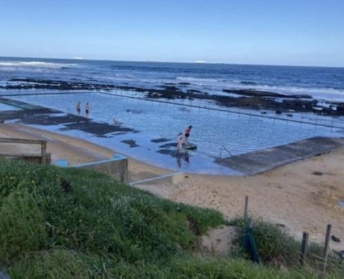 a swimming pool on the beach next to the ocean at Marlo's Escape - A Generous Haven for Couples in Wollongong