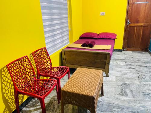 a bedroom with a bed and two chairs and a table at Night Space hostel in Kalpetta