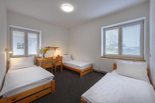 a room with two beds and a desk and a table at U rybníka Smrčná in Nová Bystřice