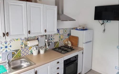 cocina con armarios blancos, fregadero y nevera en Sogno Mediterraneo, en Formia