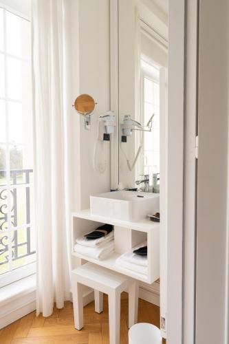 a white bathroom with a sink and a mirror at Les Garennes - Hôtel Spa Bénodet in Bénodet