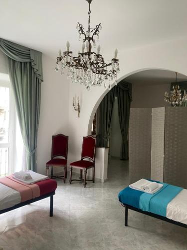1 dormitorio con 2 camas, sillas y lámpara de araña en Maison Marisa, en La Spezia