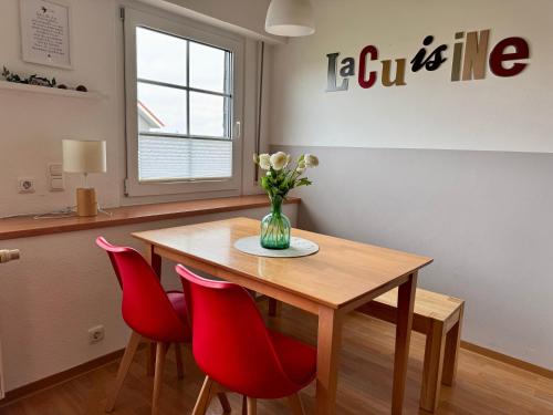 a dining room table with red chairs and a vase of flowers at Ferienhof Wübbold - Trollblume in Rieste