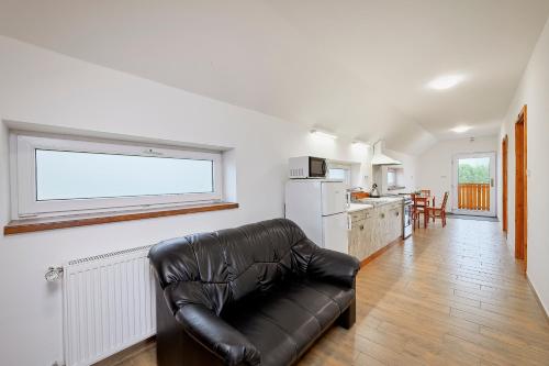 a leather couch in a living room with a kitchen at U rybníka Smrčná in Nová Bystřice
