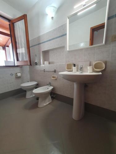 La salle de bains est pourvue de 2 toilettes, d'un lavabo et d'un miroir. dans l'établissement Angolo del Mare - Casa Corallo Nero, à Favignana