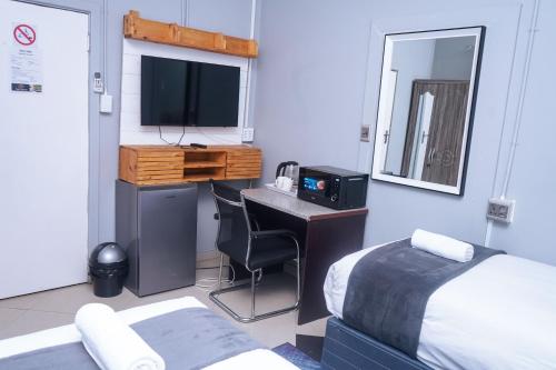 a bedroom with a bed and a desk with a television at Safi Suites and Conference Centre in Mthatha