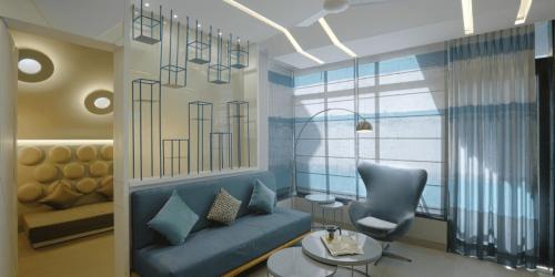 a living room with a blue couch and a chair at Neonz Resort & Club in Anand