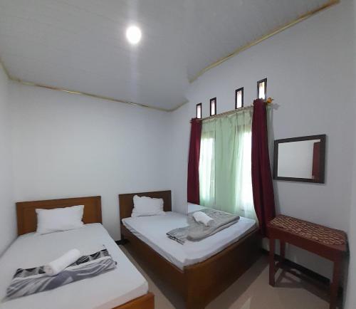 een kamer met 2 bedden, een stoel en een raam bij The Twins Homestay in Rantepao