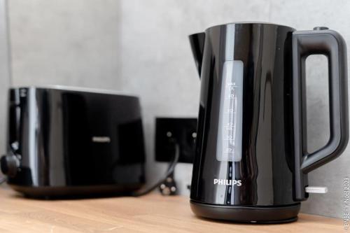 a black coffee pot sitting on a table next to a microwave at Petite Dinant - Feet in water hands on the rock in Dinant