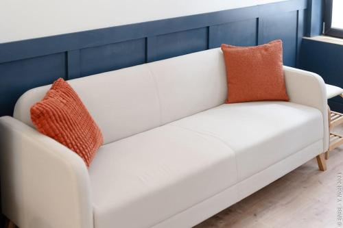 a white couch with two orange pillows on it at Petite Dinant - Feet in water hands on the rock in Dinant