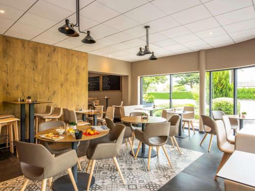 a restaurant with tables and chairs and windows at ibis Nuits Saint Georges in Nuits-Saint-Georges
