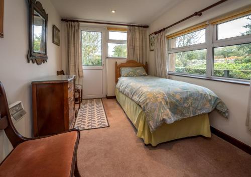 um quarto com uma cama, uma cómoda e 2 janelas em The Cottage em Llanbedrog
