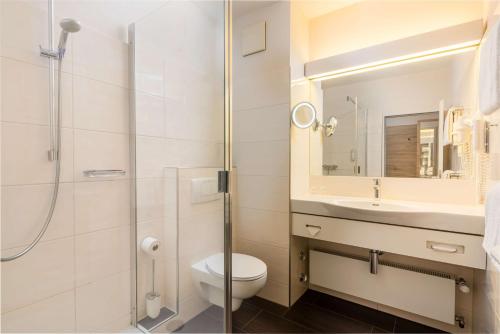 a bathroom with a toilet and a sink and a shower at Best Western Hotel Lippstadt in Lippstadt
