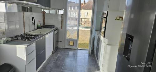 une cuisine avec des appareils blancs et une grande fenêtre dans l'établissement Pavillon avec jardin clos au bord de l'Yonne, à Coulanges-sur-Yonne