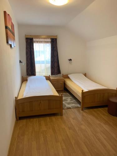 a room with two beds and a window at Adina Vendégház in Sîncraiu