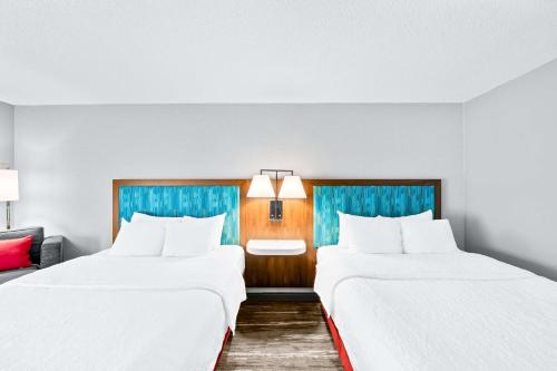 2 Betten in einem Hotelzimmer mit weißer Bettwäsche in der Unterkunft Hampton Inn South Heritage Park in Lincoln