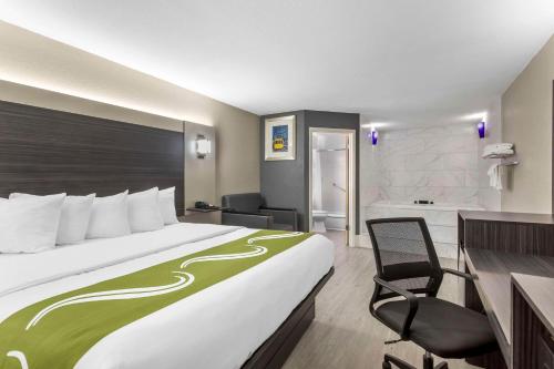 una habitación de hotel con una cama grande y una silla en Quality Inn Gainesville near University, en Gainesville