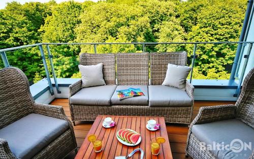 a balcony with two wicker chairs and a table at Apartamenty BalticON Nadmorskie Tarasy in Kołobrzeg