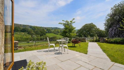 a patio with two chairs and a table with a view at Tranquil countryside cottage for two in Wrexham