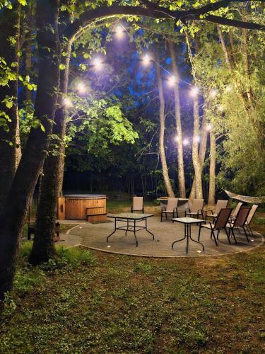 a group of tables and chairs in a park at night at Lauku viesu māja Bajāri in Rucava
