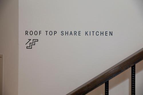 a white wall with the words roof top share kitchen on it at HakoBA Hakodate by THE SHARE HOTELS in Hakodate
