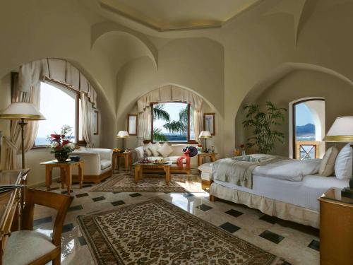 Movenpick Resort Sharm El Sheikh في شرم الشيخ: غرفة نوم مع سرير وغرفة معيشة