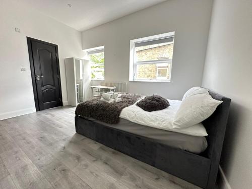 um quarto com uma cama com lençóis brancos e uma janela em Luxury studio flat em Londres