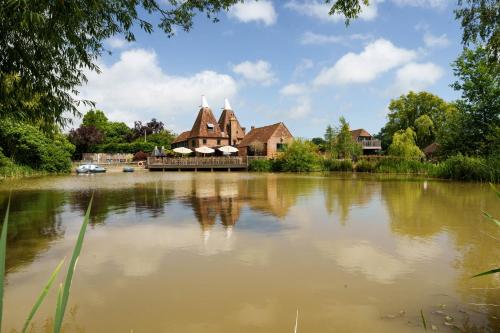a house sitting on the side of a lake at Vineyard Oast Sleeps 25 in Wavehorne