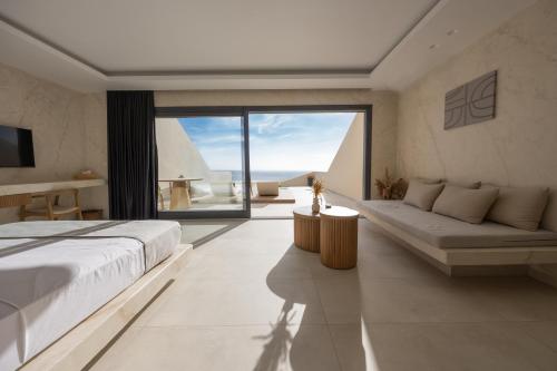 a bedroom with a large bed and a large window at Pnoe Luxury Suites in Fira