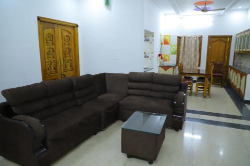 a living room with a brown couch and a table at Nanda Mohan Homestay- Luxuries AC Apartment close to Alipiri Foothills-Kapila Teertham and ISKCON temple in Tirupati