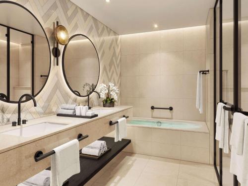 a bathroom with a tub and a sink and a mirror at Sofitel Al Hamra Beach Resort in Ras al Khaimah