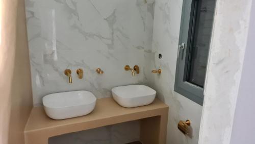 a bathroom with two white sinks and a mirror at Aegean Sunset in Agios Sostis