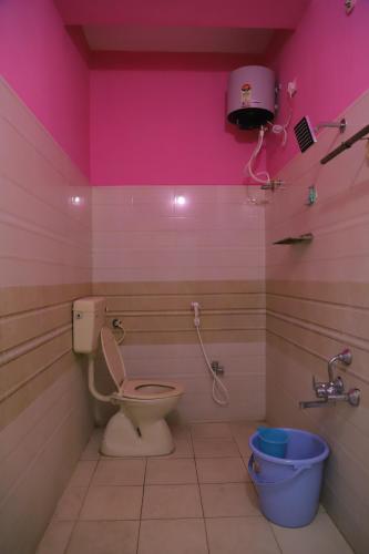 a pink bathroom with a toilet and a bucket at Nanda Mohan Homestay- Luxuries AC Apartment close to Alipiri Foothills-Kapila Teertham and ISKCON temple in Tirupati