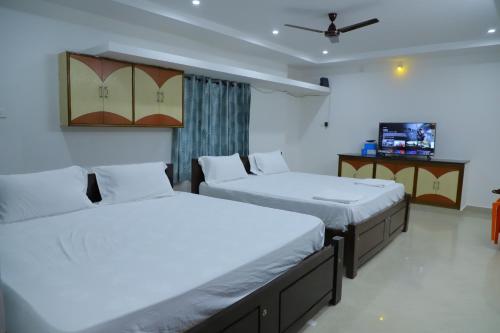 sypialnia z dwoma łóżkami i telewizorem w obiekcie Nanda Mohan Homestay- Luxury AC Apartment close to Alipiri Kapila Teertha and ISKON temples w mieście Tirupati
