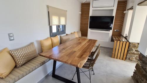 a dining room with a wooden table and a couch at Aegean Sunset in Agios Sostis