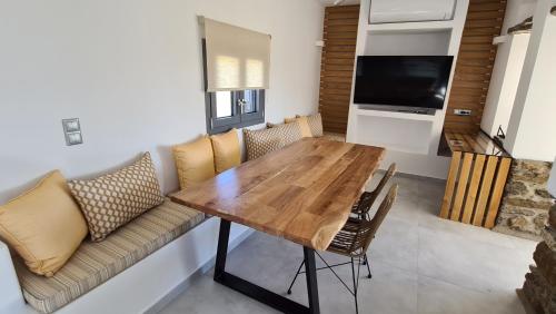 a dining room with a wooden table and a couch at Aegean Sunset in Agios Sostis