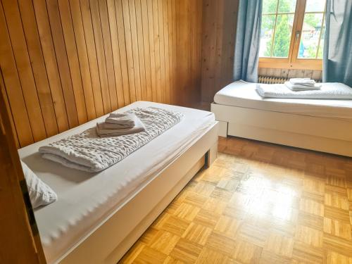 two beds in a room with wooden walls and wooden floors at Abendberg - zentral nähe Bahnhof in Wilderswil