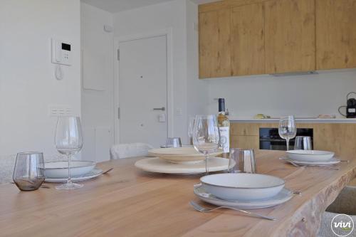 Una mesa de madera con copas de vino y platos encima. en ViVi Homes - Levalin Wellness, Pool & Terrace, en Fuengirola