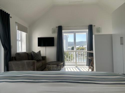 1 dormitorio con cama, sofá y balcón en Thesen View - exquisite views with bikes & canoe, en Knysna