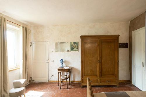 Cette chambre comprend une armoire en bois et une table. dans l'établissement Antica Casa Santa Maria Giardino, à Pomaro Monferrato