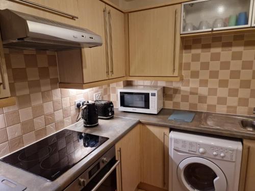 a kitchen with a washer and a microwave at 2 Bed Flat - Sleeps 4 - Parking - Wifi in Southampton