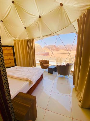 a bedroom with a bed and a large window at Youssef camp Wadi Rum in Wadi Rum