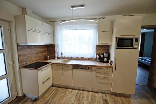 a small kitchen with white cabinets and a window at Laura Villa in Balatonlelle
