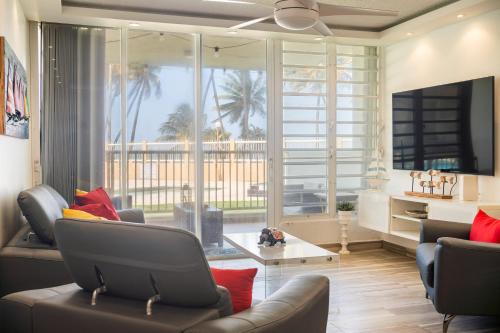 a living room with a couch and chairs and a large window at Ocean Blue Beach Apt in Luquillo