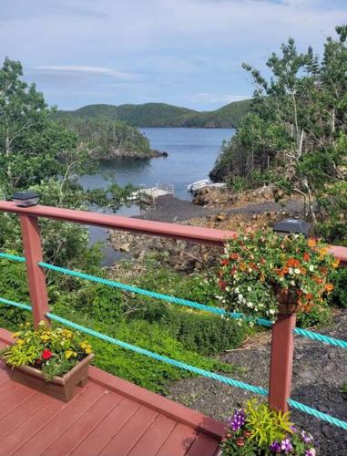 a deck with two potted plants and a body of water at Hatchet Harbour Vacation Home in Herring Neck