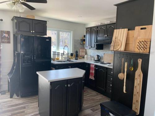 a kitchen with black cabinets and a black refrigerator at Hatchet Harbour Vacation Home in Herring Neck