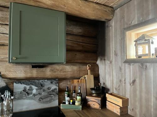 a green cabinet hanging on a wall with wine bottles at Rudland Gård - Unik gårdsovernatting i stabbur fra 1750 in Sør-Fron