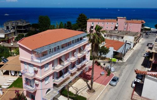 einen Luftblick auf ein rosafarbenes Gebäude in einer Stadtstraße in der Unterkunft Anemos Studios & Apartments in Póros